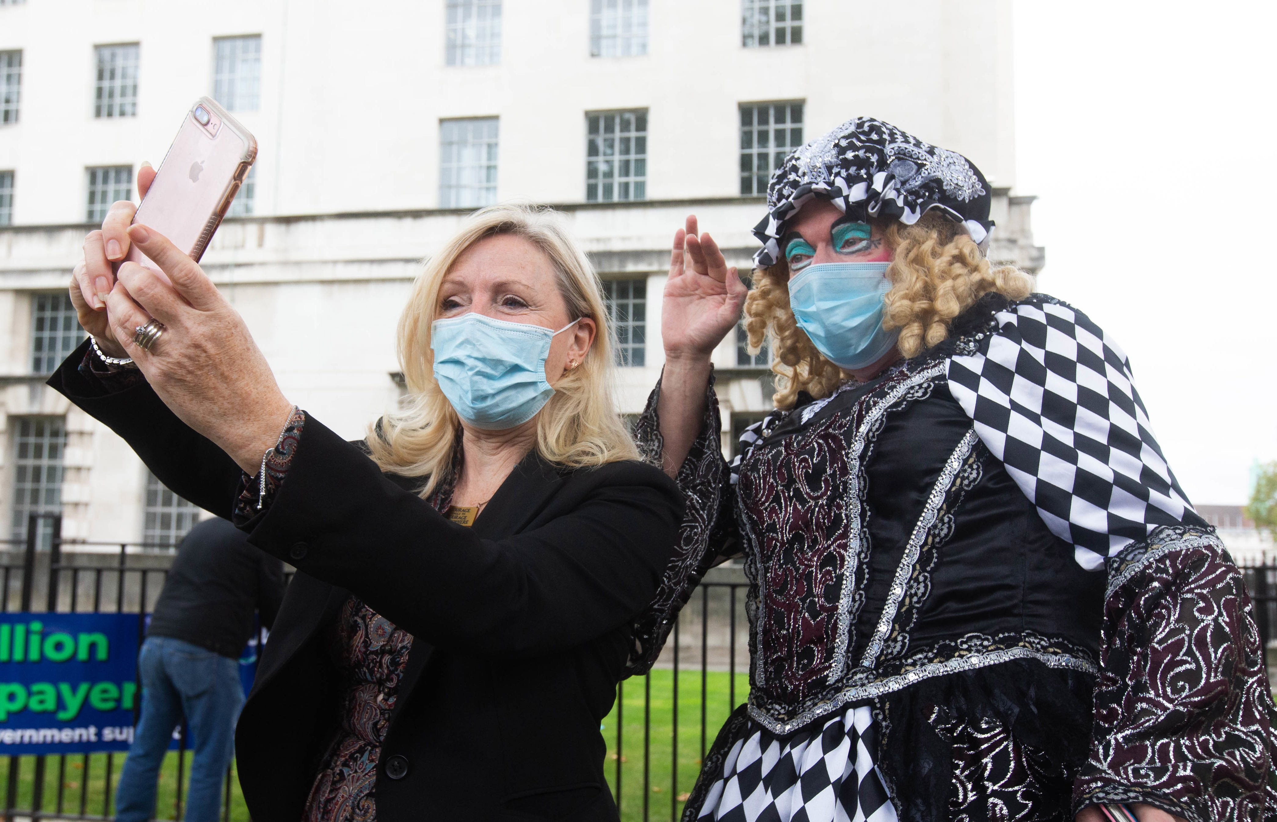 Photo shows politician and panto performer taking a selfie photo while wearing face masks